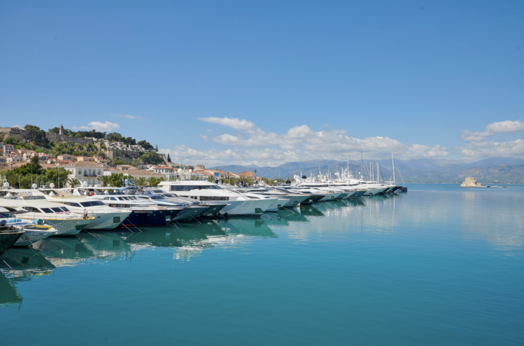 Mediterranean villas with terracotta roofs slope gently toward a sea so glassy and blue it practically melts into the sky. Between the villas and the sea there is a boardwalk where a long line of yachts... at least 20 abreast.. recedes into the distance.